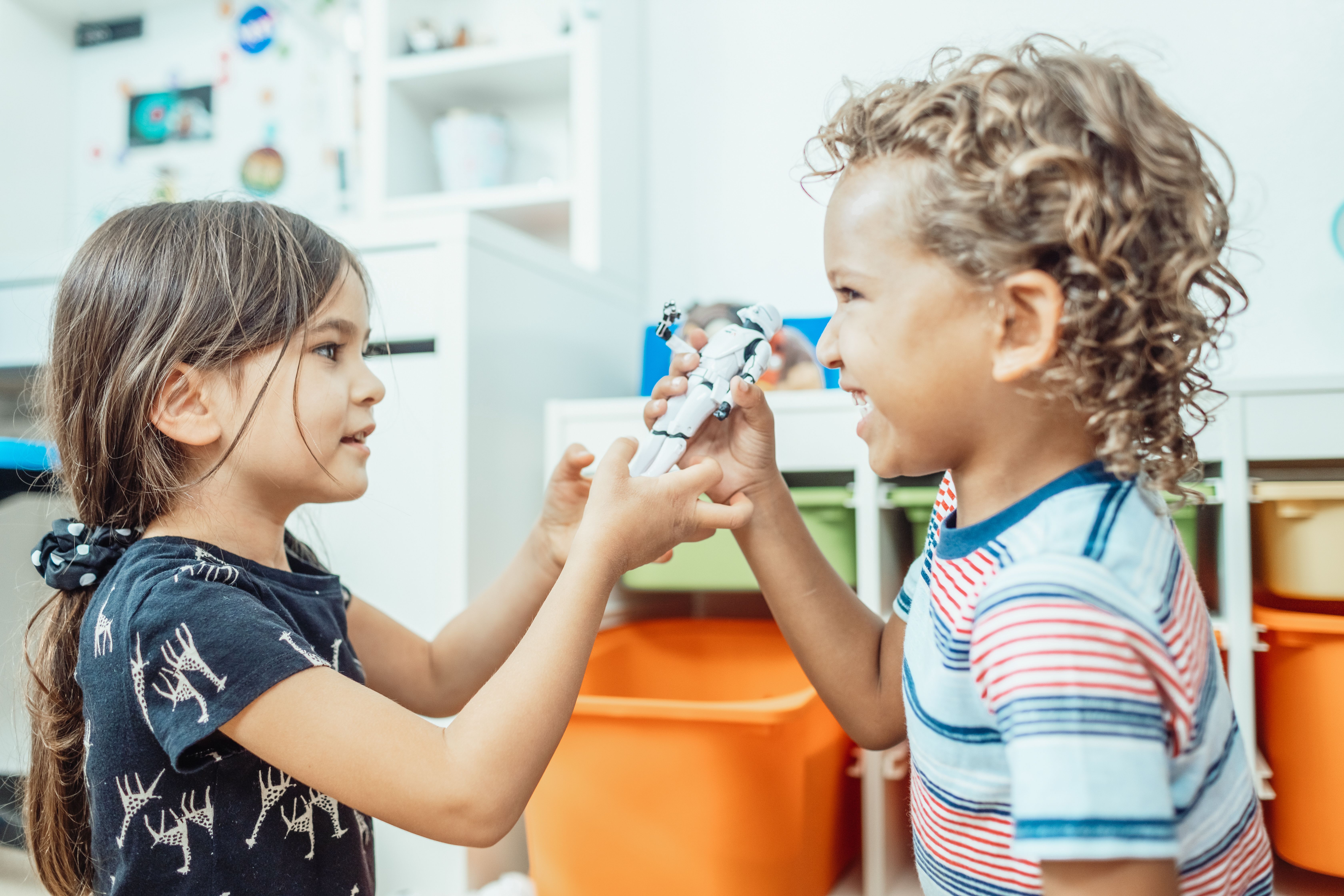 Two children sharing a toy joyfully, demonstrating cooperation and fairness