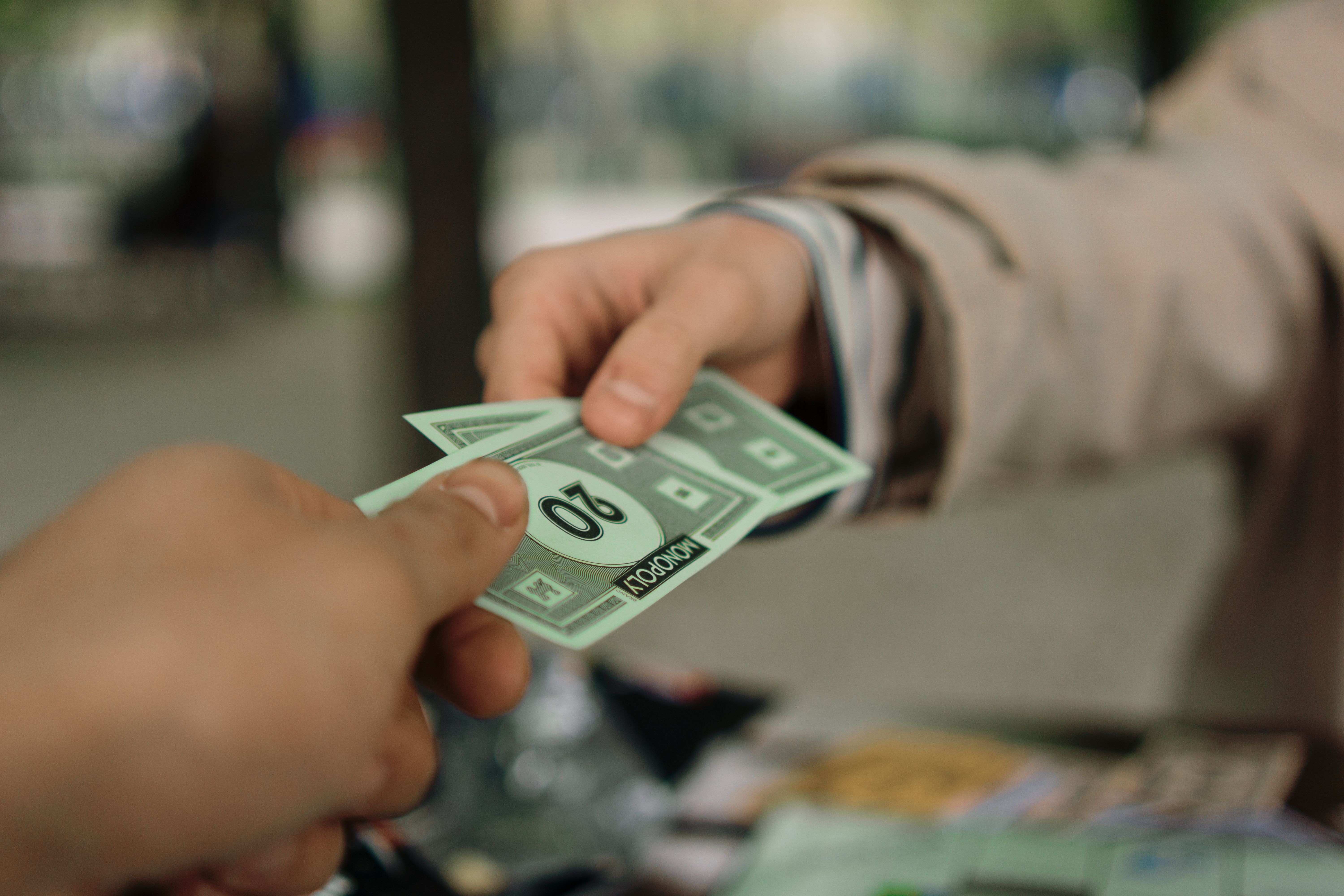 Hands exchanging play money during a family board game, illustrating lessons on fairness and greed