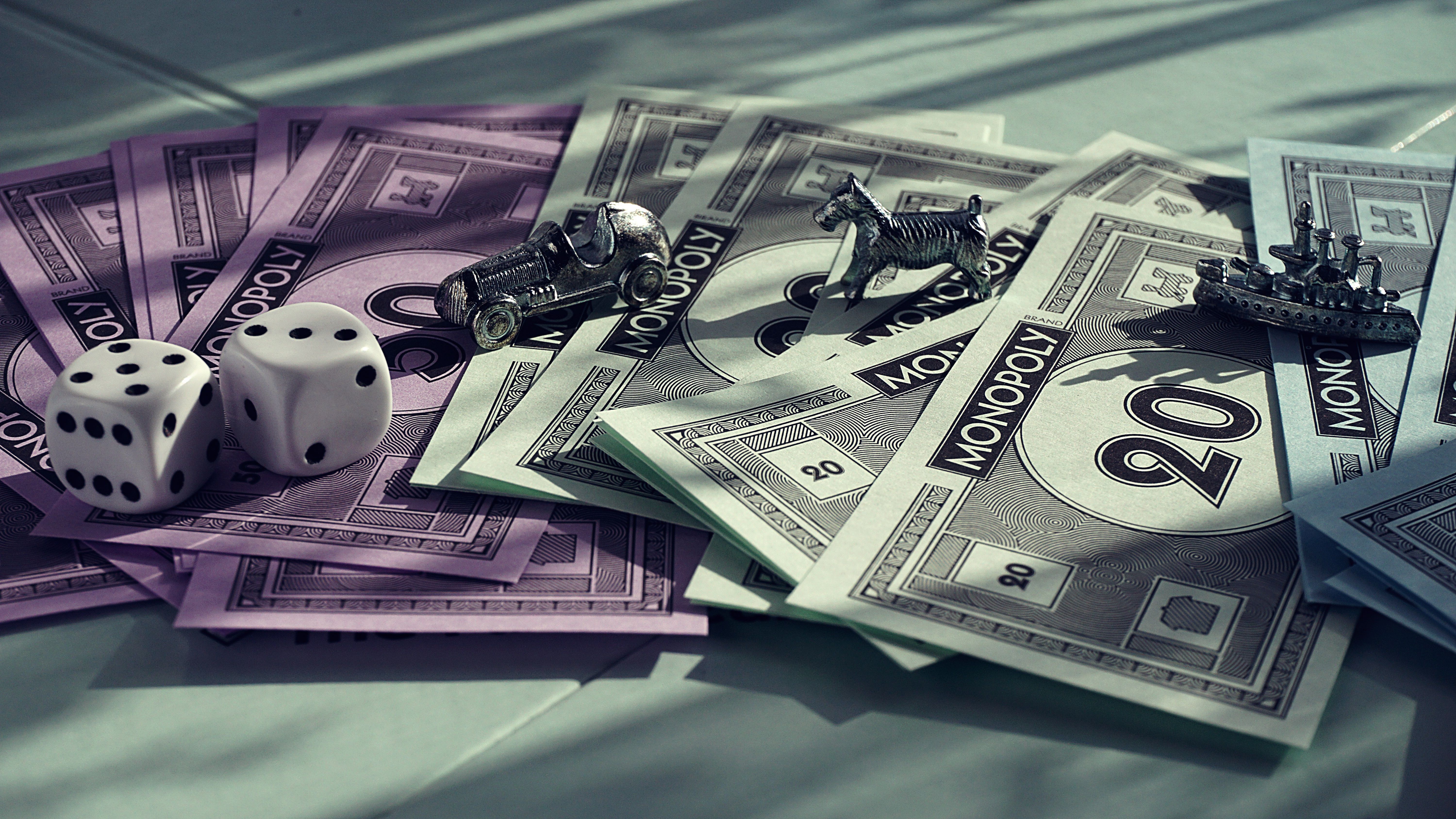 Close-up of Monopoly-style game pieces, dice, and play money symbolizing power and greed themes