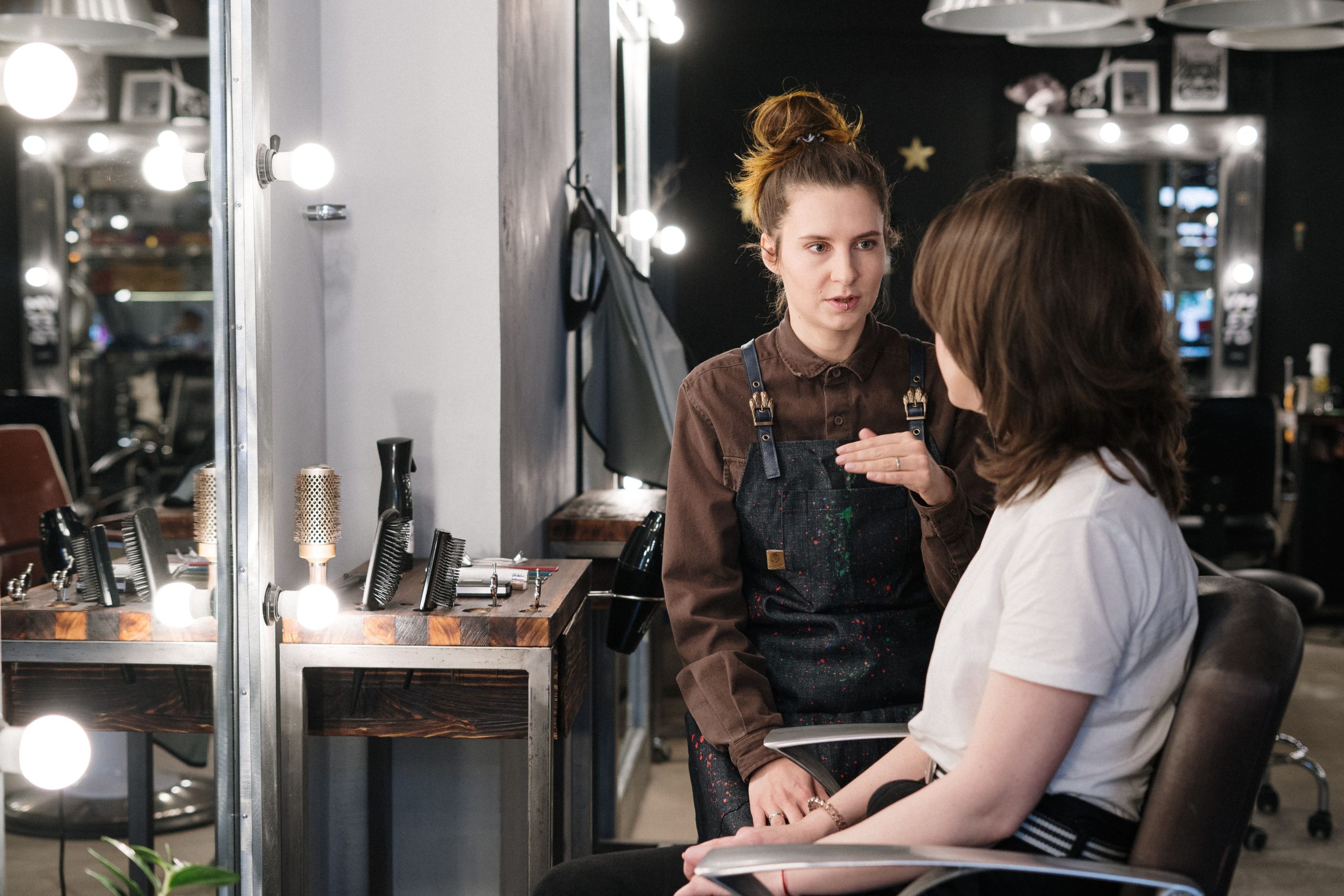 Hair stylist listening to a client during a personal consultation in a salon.