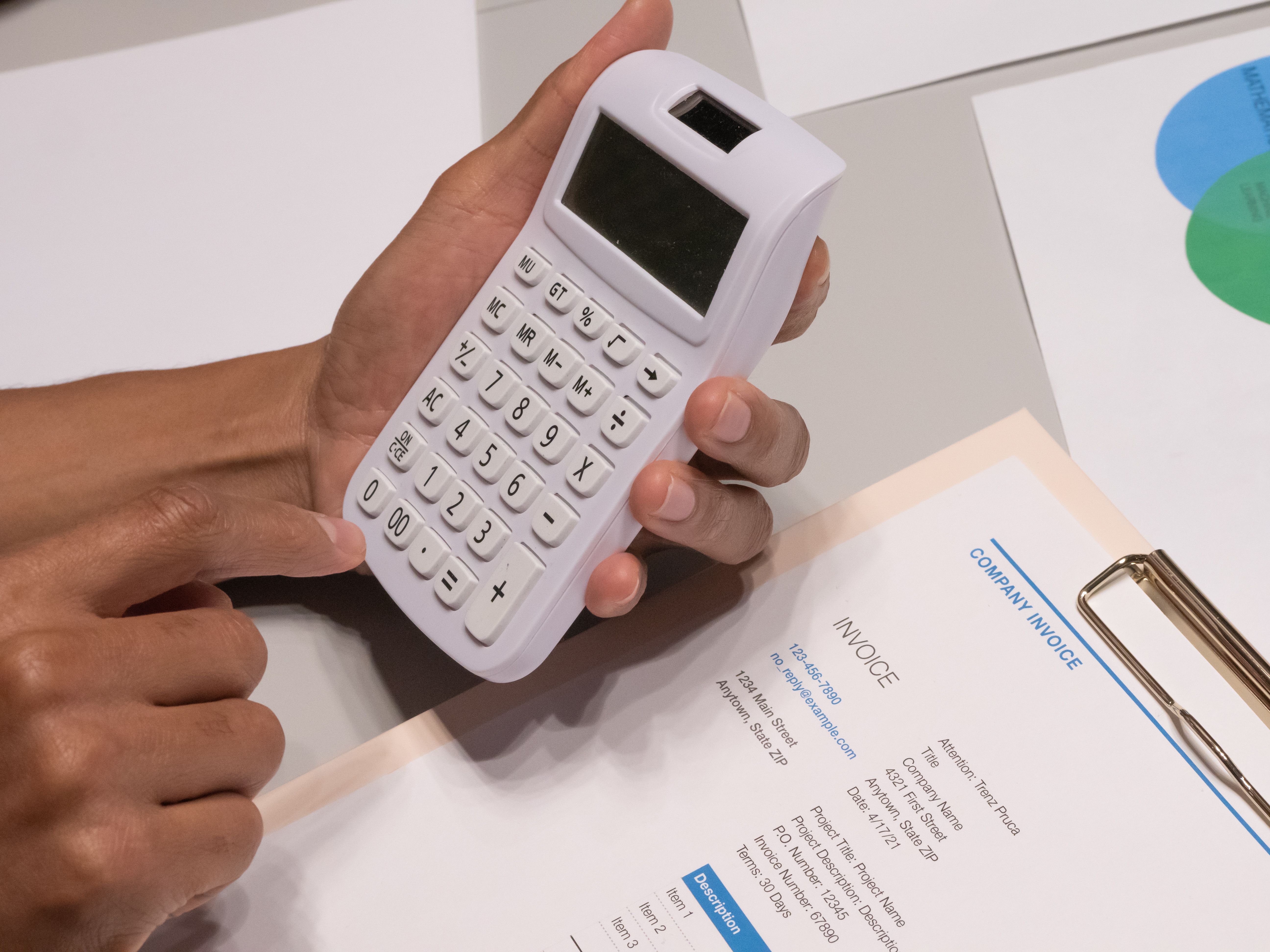 Hands using a calculator next to an invoice, representing hourly billing and calculating legal fees in a civil case