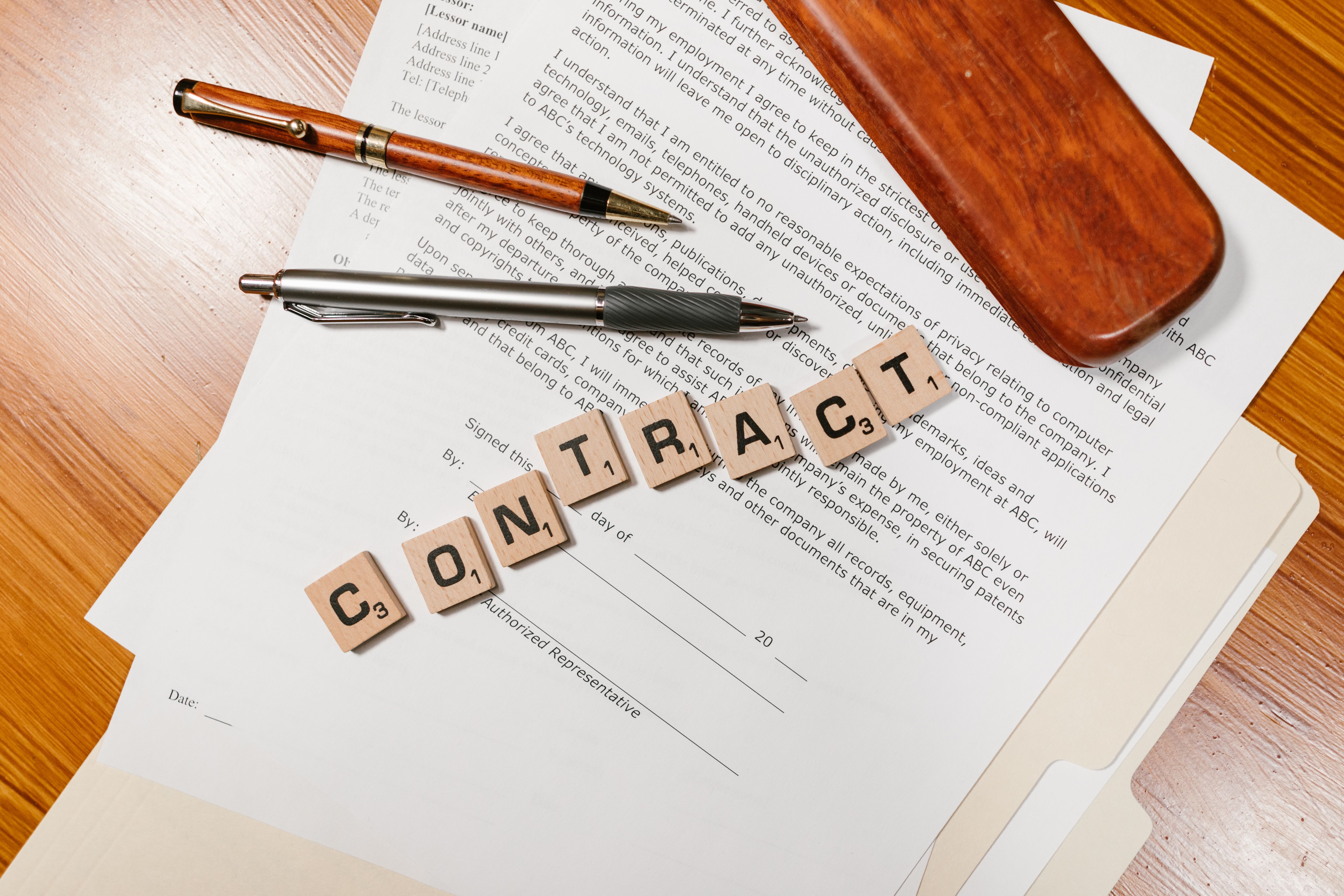 Close-up of contract papers with Scrabble tiles spelling CONTRACT