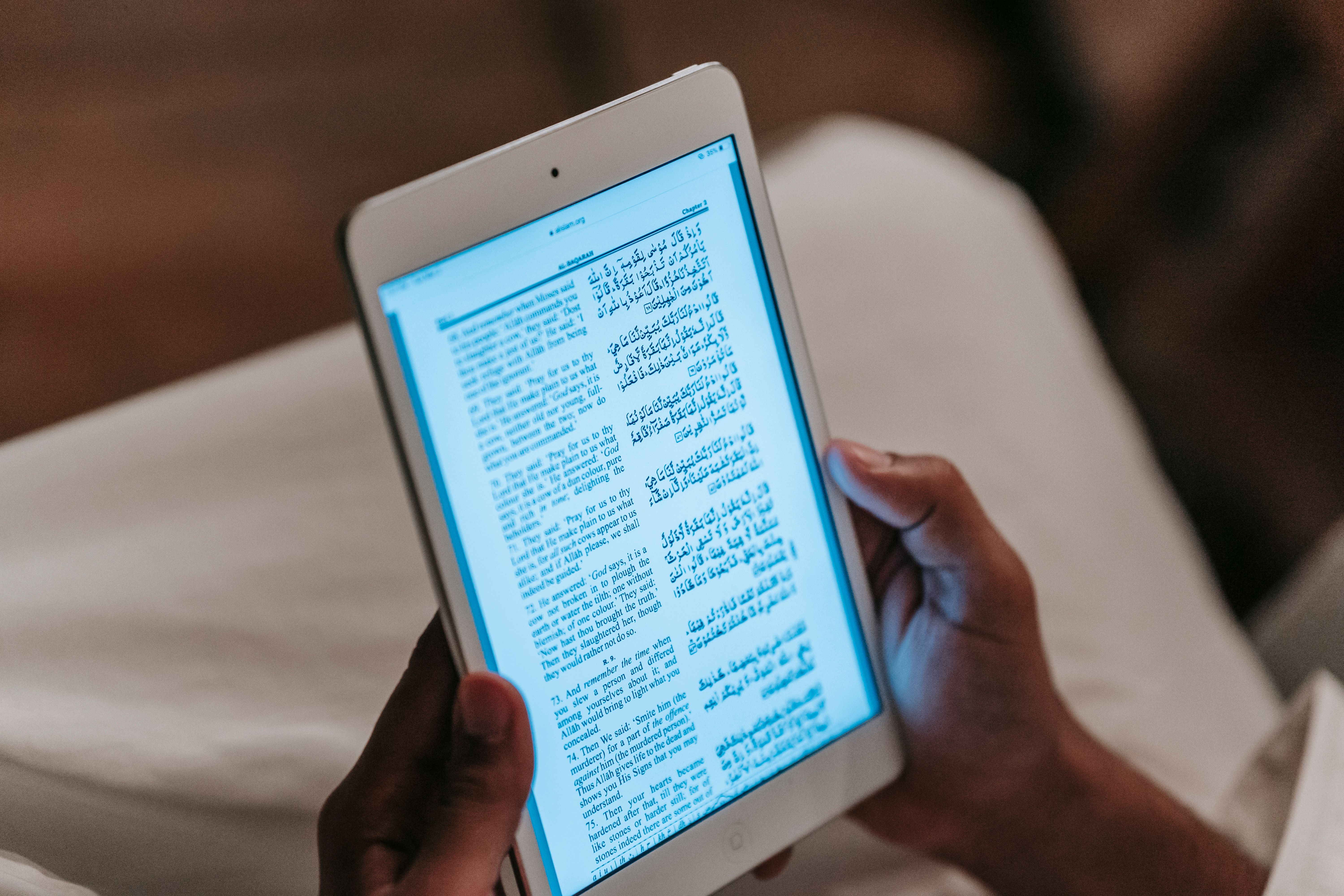Person reading text on a tablet against a blurred room background