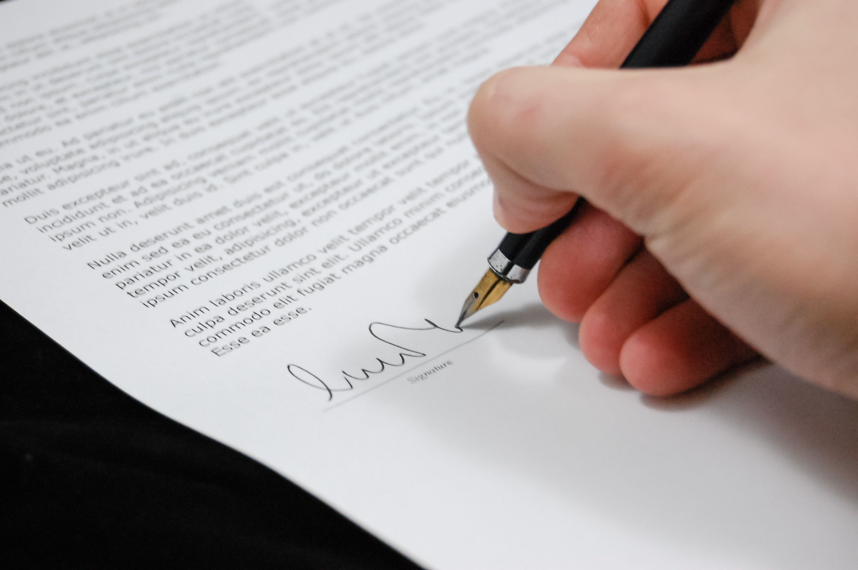Hand signing a legal document with a fountain pen, symbolizing a retainer agreement and fee arrangement