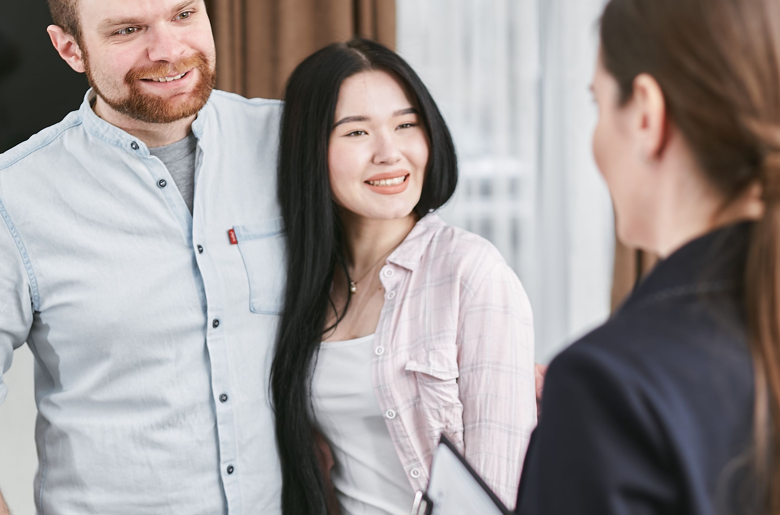 Smiling couple speaking with a professional advisor in a relaxed indoor setting.